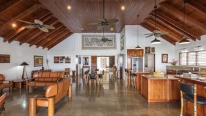 A spacious living area with a high ceiling, wooden beams, and a central island with seating. - Sea Winds Luxury Villas (Korolevu)