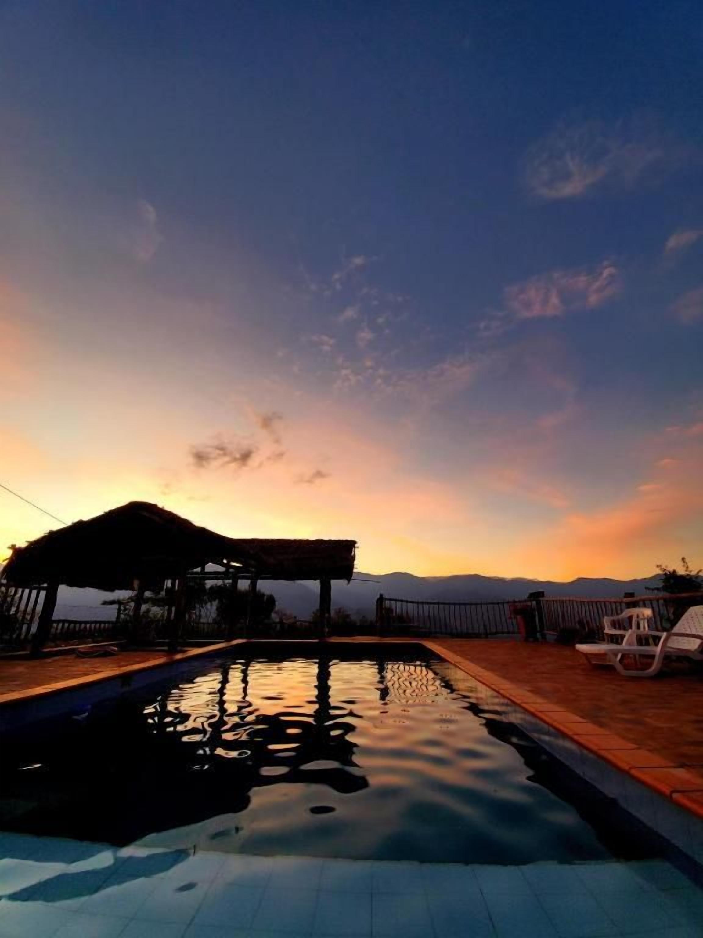 Una piscina con vistas a montañas al atardecer.