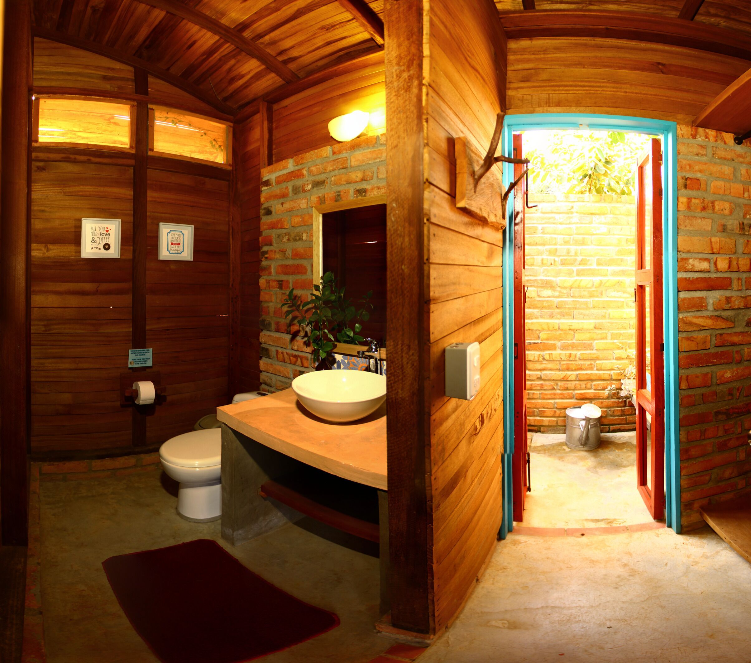 A wooden bathroom with a sink, toilet, and a mirror.