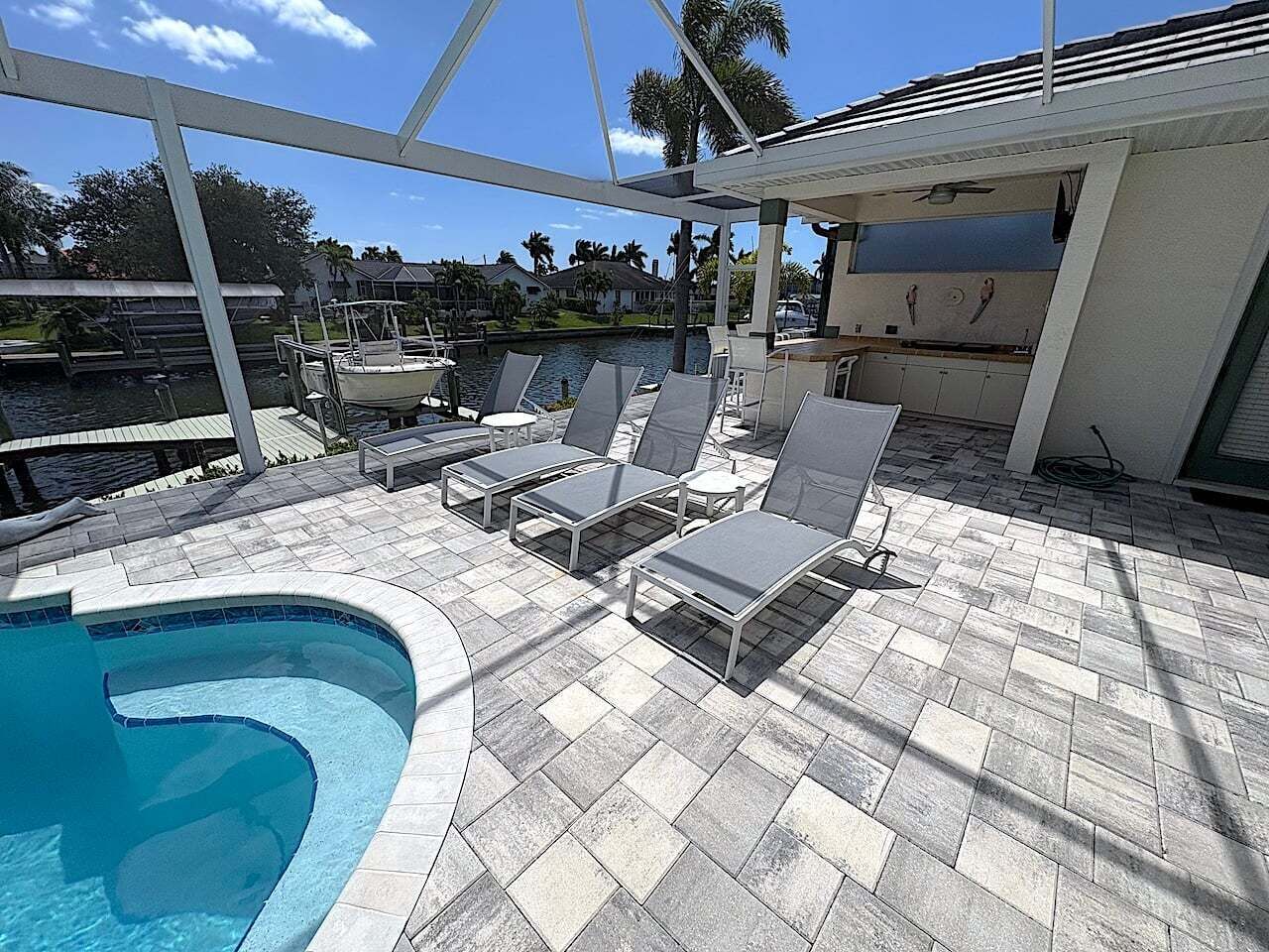 Un espace piscine comprenant des chaises longues, une piscine et un patio couvert.