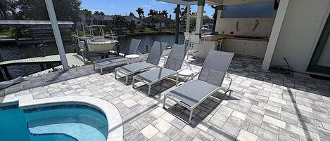 Un espace piscine comprenant des chaises longues, une piscine et un patio couvert.