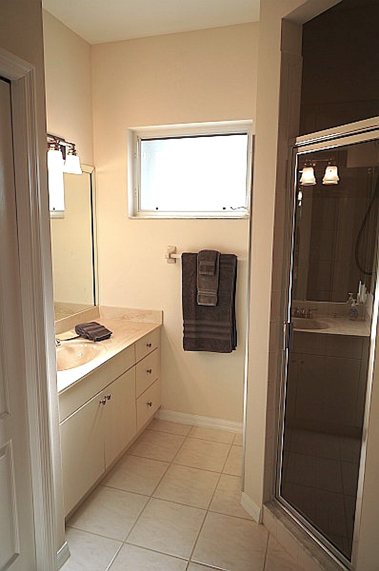 A bathroom with a sink, mirror, towel rack, and a shower area.
