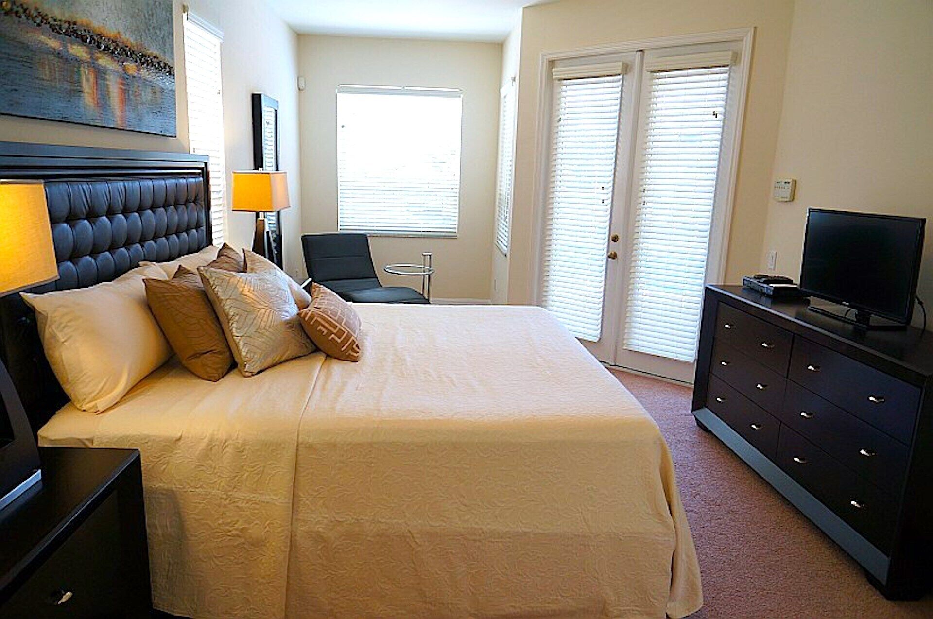 A hotel room with a large bed, a television, a desk, and a chair.