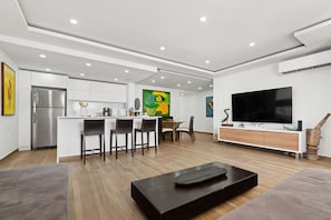 A modern living room with a large flat-screen TV, a dark coffee table, and a sofa.