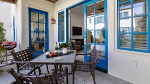 Un patio con mesa y sillas, una parrilla y un televisor al fondo.