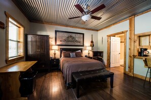 Une chambre à coucher comprenant un lit, des tables de chevet, un bureau et un ventilateur de plafond.