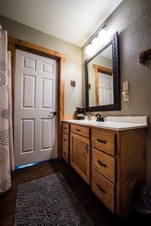 Une salle de bain avec un meuble-lavabo en bois, un grand miroir et un lavabo blanc.