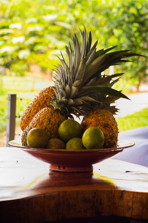 Een schaal ananas en lime op een houten tafel, met een onscherpe groene achtergrond.