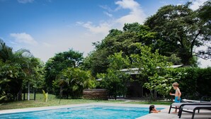 A swimming pool with a clear blue water, surrounded by lush greenery and trees.