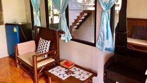 A room with a wooden bed, a chair with a cushion, a small table with a mat, and curtains. - KOANA Bungalows (Ko Pha-ngan)