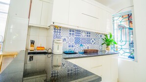 A kitchen with white cabinets, blue and white patterned backsplash, and a window with blue iron bars. - Endless Love House in Old Quarter Hanoi (Hanoi)