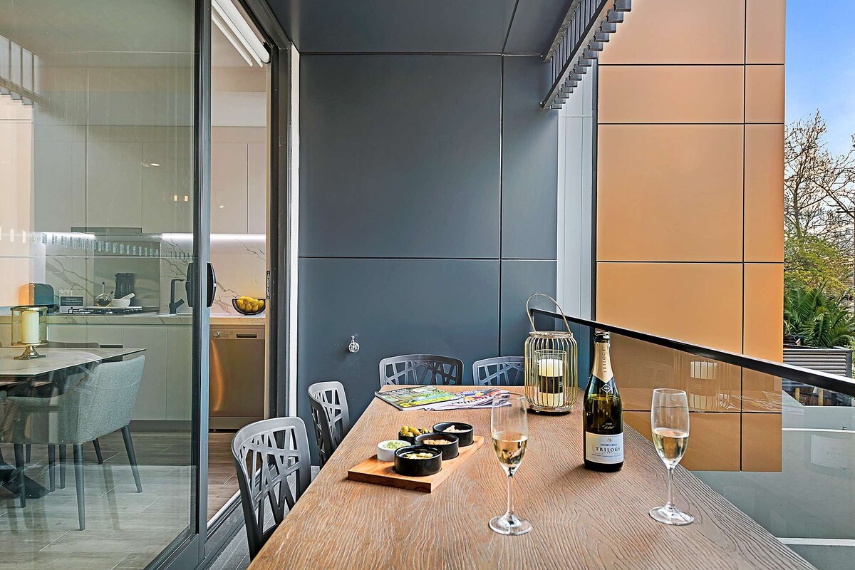 Een eetgedeelte met een houten tafel, stoelen, een fles wijn en glazen.