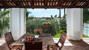 A wooden table with chairs and a potted plant on a terrace with a view of a swimming pool and greenery. - House near the sea, with shared pool, Marsala, Sicily - Marsala 2 (Marsala)