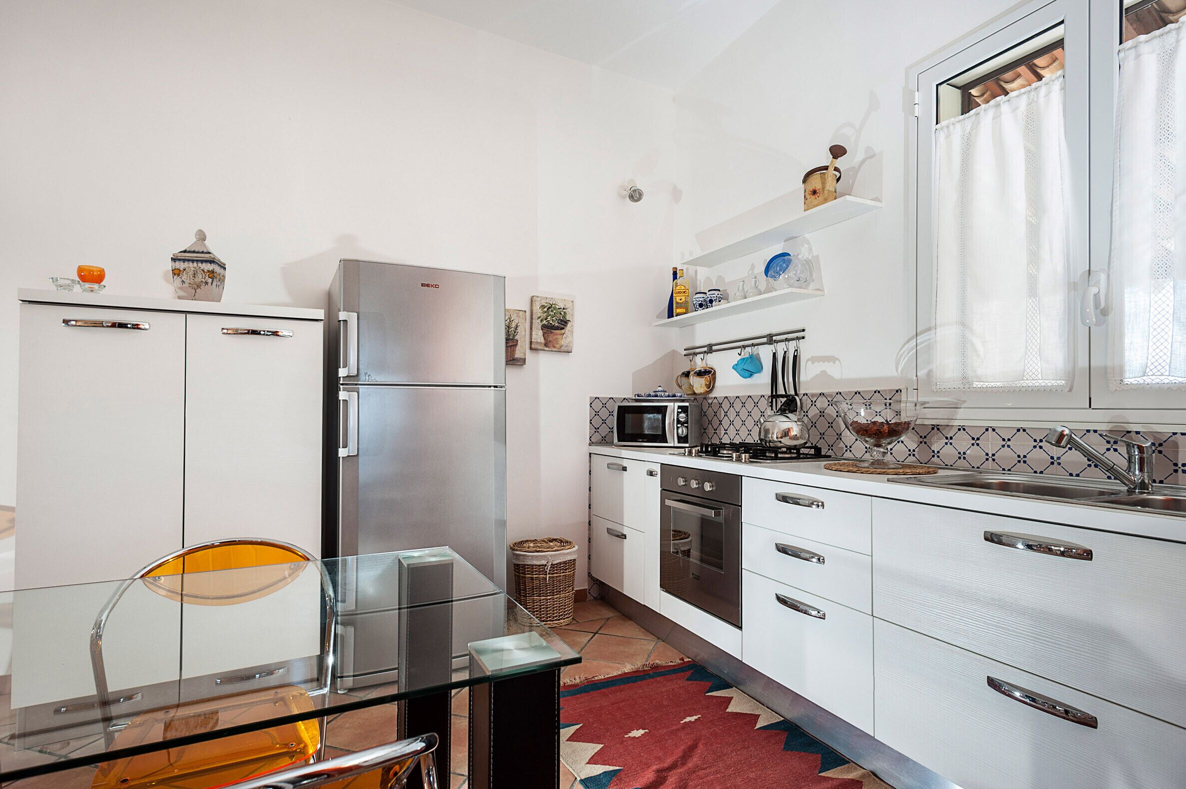 Une cuisine moderne avec des meubles blancs, des appareils en acier inoxydable et une table à manger en verre.