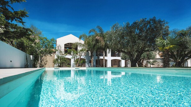 A clear swimming pool with a white building in the background, surrounded by trees. - House near the sea, with shared pool, Marsala, Sicily - Marsala 2 (Marsala)