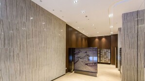 A modern hotel corridor with marble walls, wooden paneling, and a tiled floor. - HO Cotel Apartment (Chengdu)