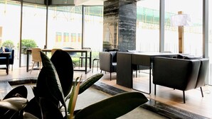 A modern interior with a dining area, large windows, and a view of construction outside. - HO Cotel Apartment (Chengdu)