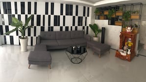 A modern living room with a sectional sofa, a glass coffee table, and potted plants. - Moc Lan 1 Hotel (Ho Chi Minh City)