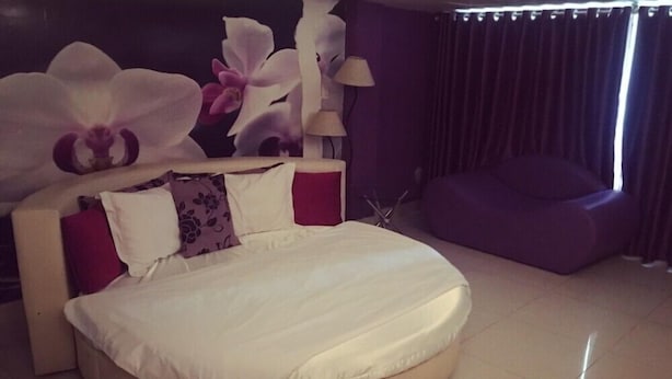 A modern bedroom with a round bed, a large window with curtains, and a purple armchair. - Moc Lan 1 Hotel (Ho Chi Minh City)