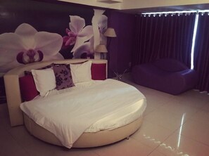 A modern bedroom with a round bed, a large window with curtains, and a purple armchair. - Moc Lan 1 Hotel (Ho Chi Minh City)