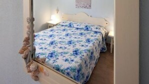 A bedroom with a bed, a nightstand, a wall-mounted mirror, and a ceiling fan. - A beautiful villaetta overlooking the sea (COSTA REI)