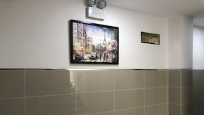 Eine Wand mit einem gerahmten Gemälde einer Straßenszene, einem Schild mit VIP-Zimmernummern und einer an der Decke befestigten Vorrichtung.