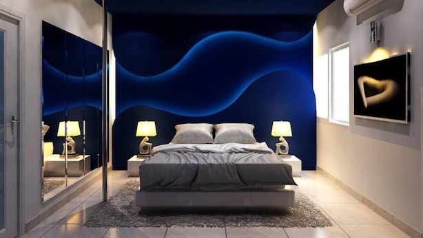 Ein modernes Schlafzimmer mit gewölbter Decke, einem großen Bett, Nachttischen und einem an der Wand montierten Fernseher.