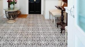 A hallway with a black door, a chandelier, a framed artwork, and a tiled floor. - Richmond on Canvas, by Veeve (London)