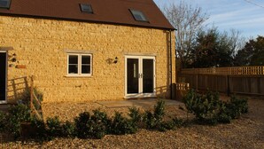 Un bâtiment en pierre avec un toit en pente, deux fenêtres et une porte.