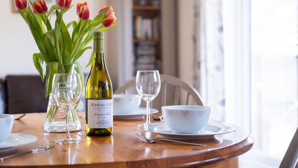 Une table à manger avec une bouteille de vin, des tulipes et un saladier.