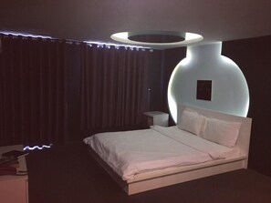 A modern bedroom with a large bed, a bedside table, and a unique circular light fixture above the bed.
