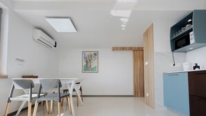 A modern kitchen with white cabinetry, a blue countertop, and a dining area with a white table and chairs. - October in Luxury Sea-View Stay near Sandy Beach (Zambratija)