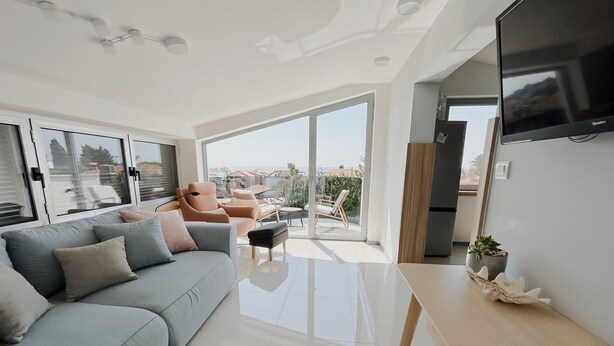 A modern living room with a grey sofa, a small table, and a TV mounted on the wall. - October in Luxury Sea-View Stay near Sandy Beach (Zambratija)