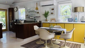 A modern kitchen with a central island, white chairs, and a yellow accent wall. - NEW!!  The “WATERSIDE” COTTAGE~With dockage (Bokeelia)