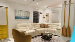 A modern living room with a beige sectional sofa, a round armchair, a glass coffee table, and a striped rug. - NEW!!  The “WATERSIDE” COTTAGE~With dockage (Bokeelia)