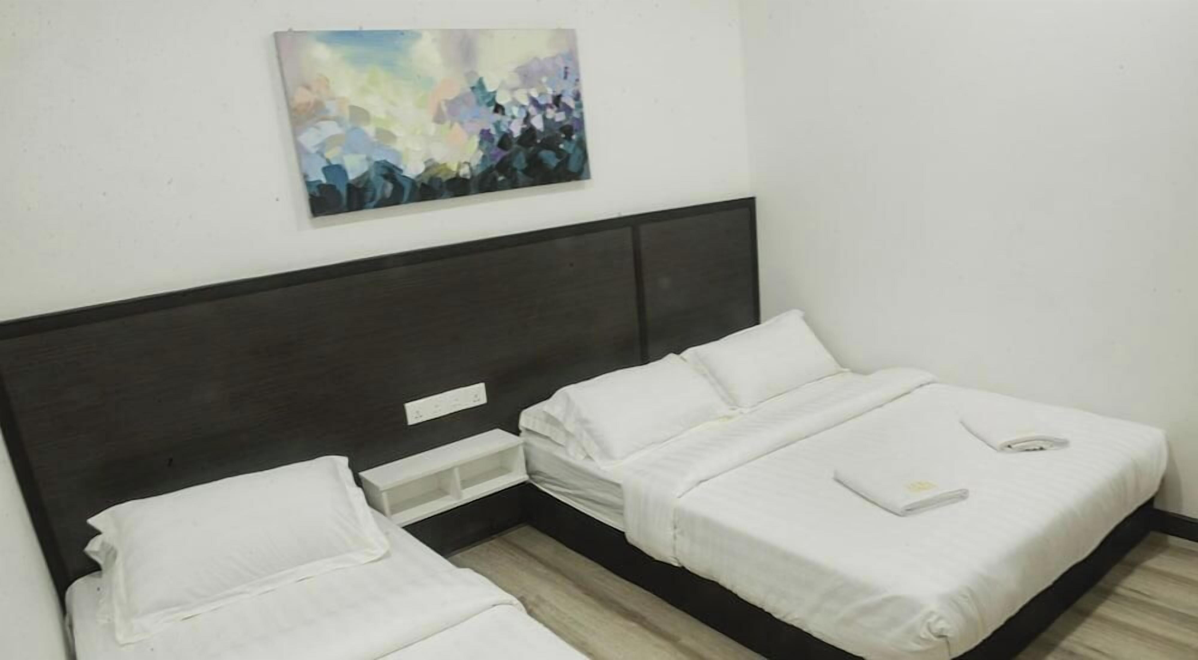 Quarto com duas camas, cabeceira escura, pintura na parede e toalha branca na cama da direita.