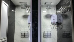 A bathroom with two shower stalls, each equipped with a handheld showerhead, a wall-mounted towel rack, and a soap dispenser.