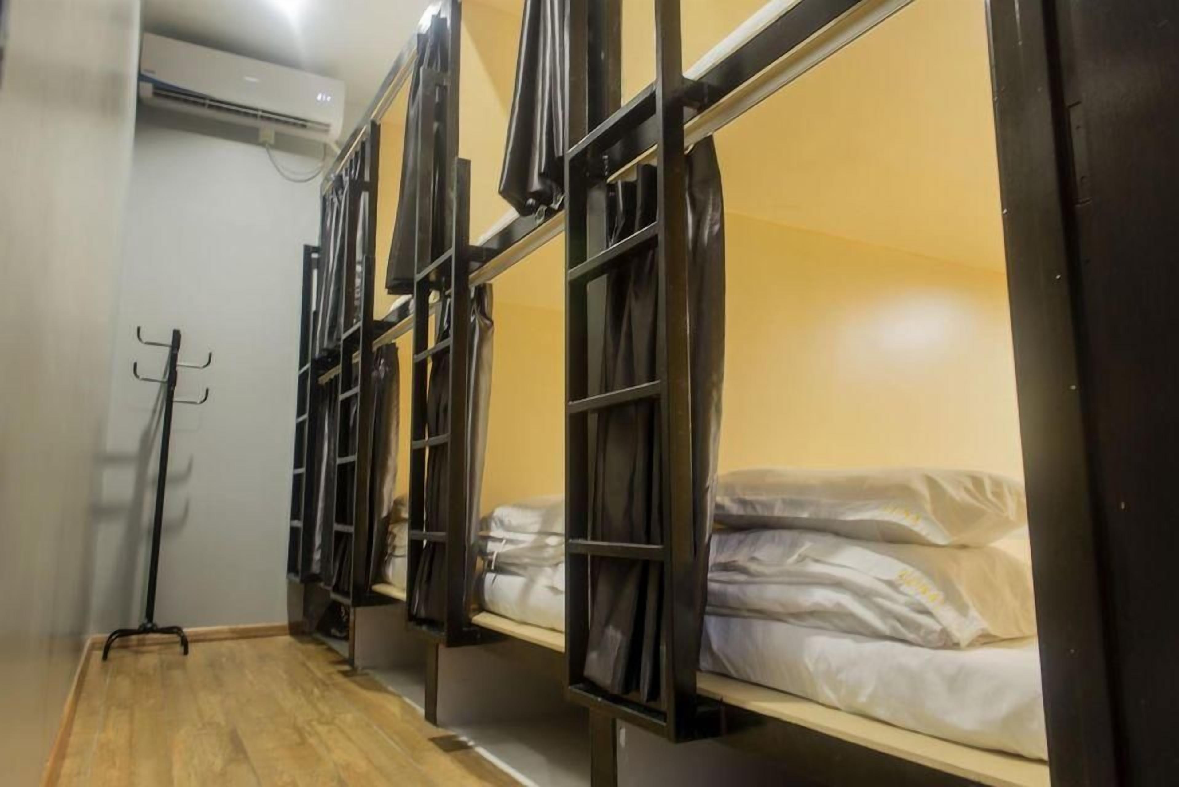 A room with bunk beds, a coat rack, and a wooden floor.