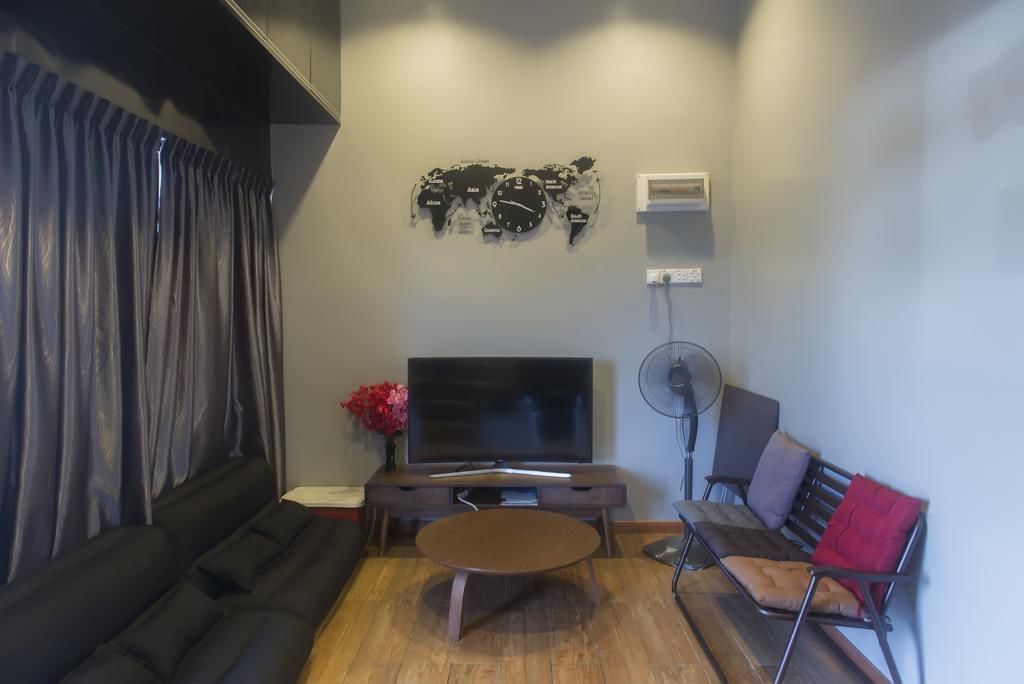 A living room with a flat-screen TV, a round coffee table, a sofa, and a red cushion.