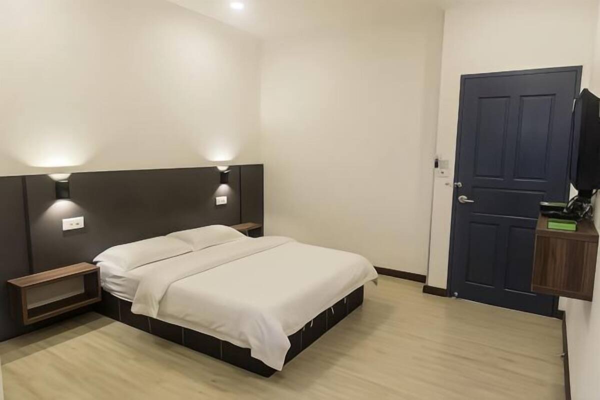 Une chambre à coucher avec un lit, des tables de chevet, une télévision et une porte.