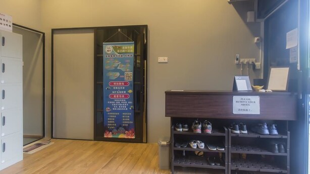 A hotel reception area with a shoe rack and a sign instructing to remove shoes. - Luna Capsule (Semporna)