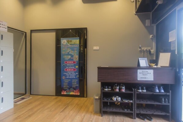 A hotel reception area with a shoe rack and a sign instructing to remove shoes. - Luna Capsule (Semporna)
