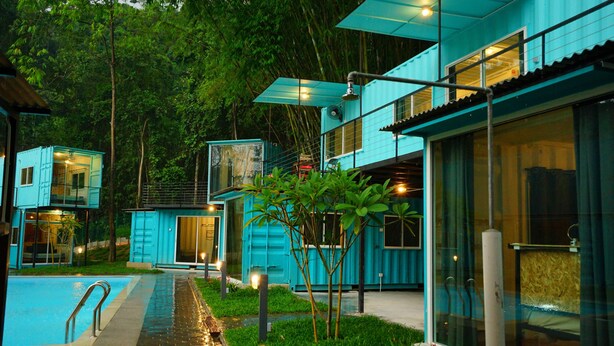 Un edificio moderno con piscina, rodeado de abundante vegetación.