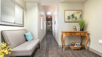 Un couloir comprenant un canapé, une console en bois, un tableau encadré et un panier en osier.