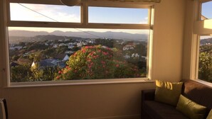 Quarto com uma janela ampla que oferece vista para uma área residencial e montanhas.