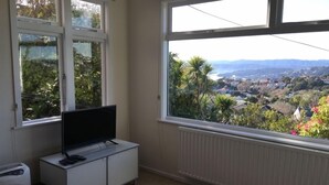 Quarto com uma grande janela que oferece vista para uma cidade e montanhas.