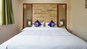 Une chambre d’hôtel avec un grand lit, deux tables de chevet, une tête de lit en bois et un rideau vert.