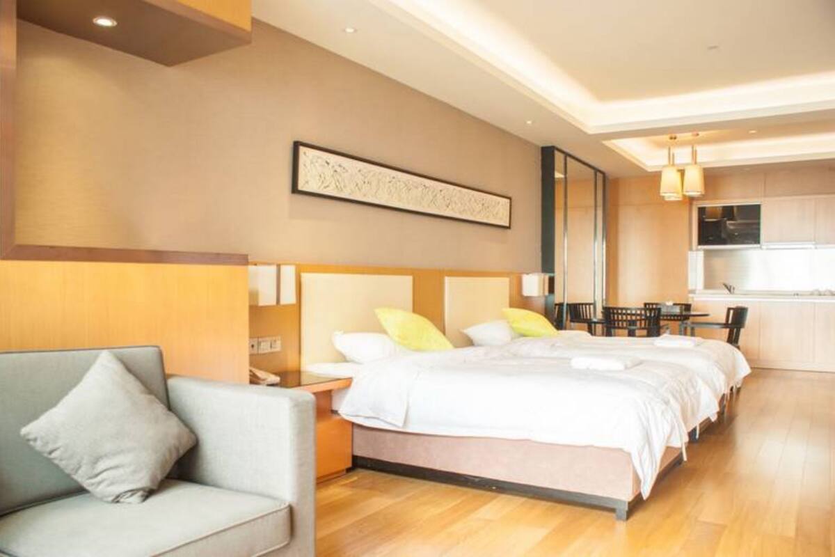 Una habitación de hotel moderna con una cama grande, un sofá, un comedor y una cocina.