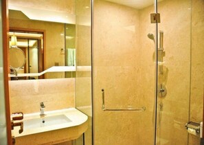 Ein modernes Badezimmer mit Duschkabine aus Glas, Waschbecken mit Spiegel und Handtuchhalter.