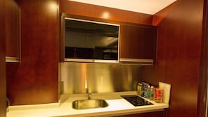 A compact kitchen with a stainless steel sink, a built-in stove, and wooden cabinets. - Guangzhou Yiyuan Apartment (Guangzhou)